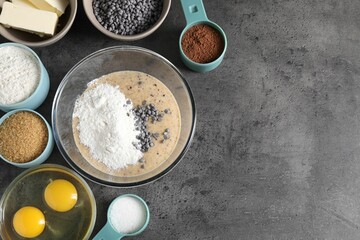 Raw dough with chocolate chips in bowl and ingredients on grey table, flat lay. Space for text