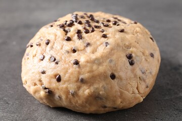 Raw dough with chocolate chips on grey table, closeup