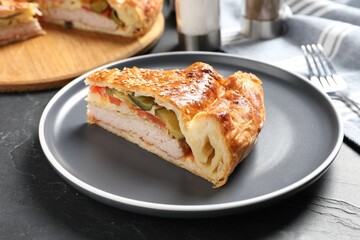 Piece of tasty homemade pie with filling on dark grey table