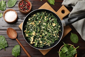 Tasty spinach dip with eggs in dish served on wooden table, flat lay