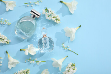 Luxury perfumes and floral decor on light blue background, flat lay. Space for text