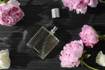 Luxury perfume and floral decor on dark background, flat lay
