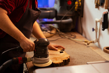 Carpenter holding power tool used to smooth surfaces by abrasion with sandpaper, using it on wood...