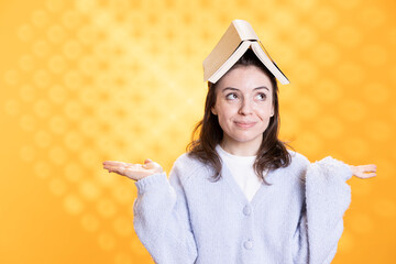 Woman with opened book on head acting zany, portraying having fun concept, isolated over studio...