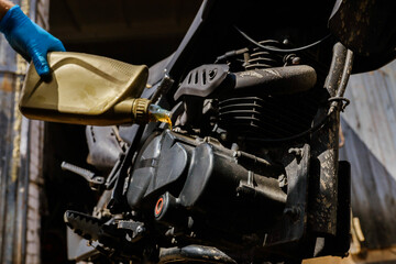 Fototapeta premium pouring new motor oil into a motorcycle engine 