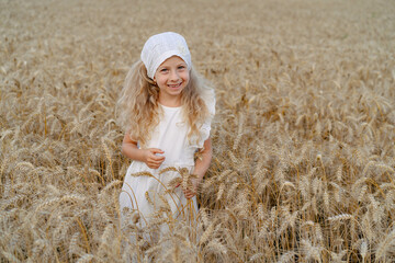 Little beautiful blonde girl with rye bread in a field of ears of rye