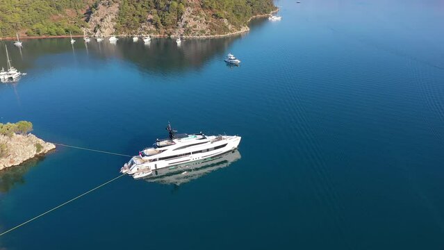 A white mega yacht with beautiful mirror reflection, moored at calm, deep blue sea. Aerial Idyllic view of Orhaniye Bay. Marmaris, Turkey
