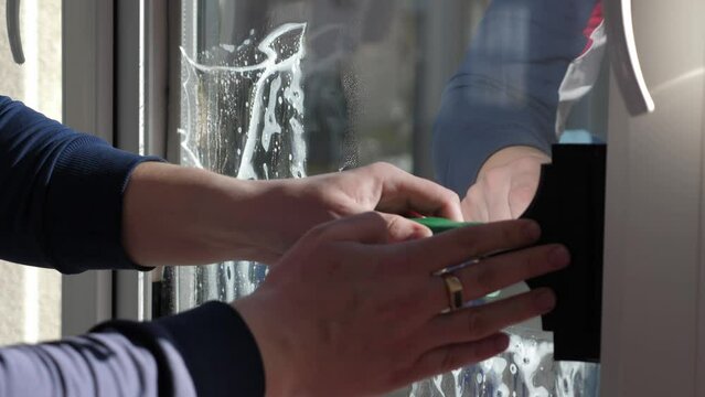 Worker installing and smoothing tint film on window at home. Man tinting windows with squeegee