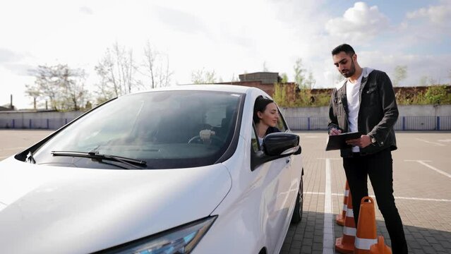 Driving instructor explaining how to drive to the female student in car. Practical test before getting a driver's license