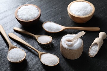 Organic white salt in bowls and spoons on black table