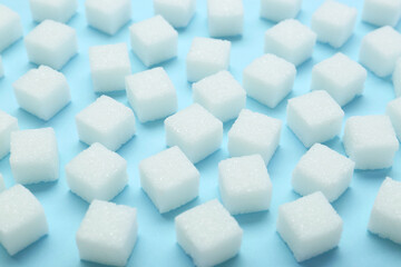 White sugar cubes on light blue background, closeup