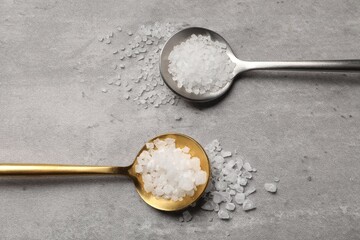 Natural salt in spoons on grey table, flat lay