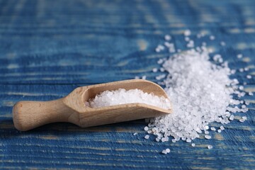 Natural salt and scoop on blue wooden table, closeup