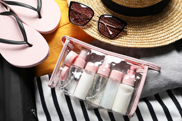 Plastic bag of cosmetic travel kit and beach accessories in suitcase, top view