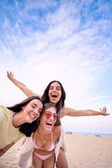 Vertical. Three attractive Caucasian women making a selfie doing piggyback looking excited at...