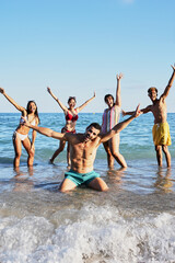 Vertical Portrait of a group of happy young people in swimming costumes posing for a photo on the...