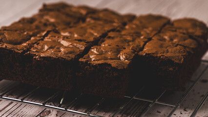 Chocolate brownies placed over a cooling rack on a wooden background. Selective focus.