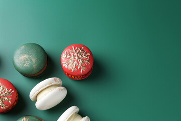Beautifully decorated Christmas macarons on green background, above view. Space for text