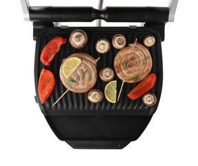 Electric grill with homemade sausages, mushrooms and bell pepper isolated on white, top view