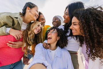 Diverse group of happy young best female friends having fun together outdoors. International youth...