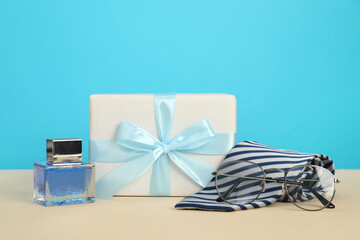 Happy Father's Day. Tie, glasses, perfume and gift box on beige table