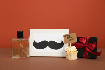 Happy Father's Day. Tasty cupcake with greetings, gift box, perfume and frame with mustache on...