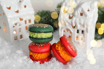 Different decorated Christmas macarons on table with artificial snow