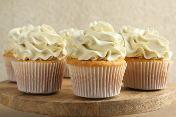 Tasty vanilla cupcakes with cream on table, closeup