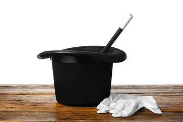Magician's hat, gloves and wand on wooden table against white background