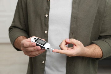 Diabetes test. Man checking blood sugar level with glucometer at home, closeup