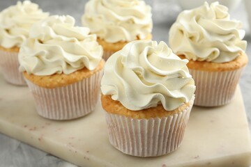 Tasty cupcakes with vanilla cream on grey table, closeup