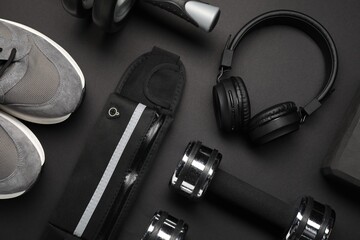 Sports equipment, headphones and sneakers on black background, flat lay