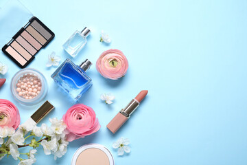 Flat lay composition with different makeup products and beautiful spring flowers on light blue background, space for text