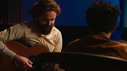 Talented artist doing live performance with his guitar in professional studio, recording new songs...
