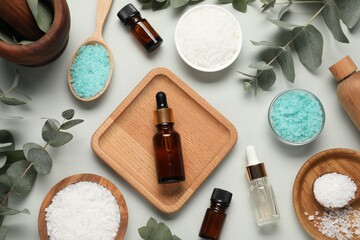 Aromatherapy products. Bottles of essential oil, sea salt and eucalyptus leaves on grey background,...