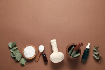 Different aromatherapy products, mortar and eucalyptus leaves on brown background, flat lay. Space...