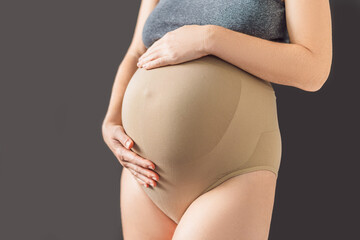Pregnant bliss: Mom-to-be embraces her baby bump with a soft fabric bandage, providing gentle...