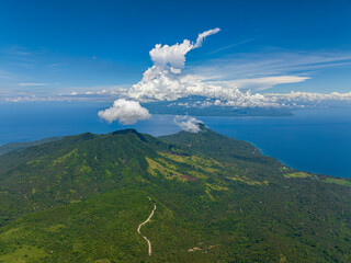 Mountain landscape with green hills and forest. Blue sky and clouds. Camiguin Island. Philippines.