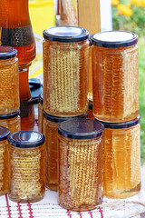 Organic honey comb and other healthy natural food in glass jars sold outside on a market