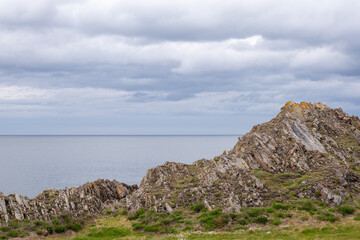 Fototapeta na wymiar 29 April 2024. Portessie,Moray,Scotland. This is the coastal rocks at Portessie with a calm sea and grey clouds.