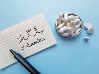 Structural chemical formula of L-carnitine with white tablets. L-carnitine is an amino acid produced by the body, also found in supplements, helps the body turn fat into energy. Dietary supplements.