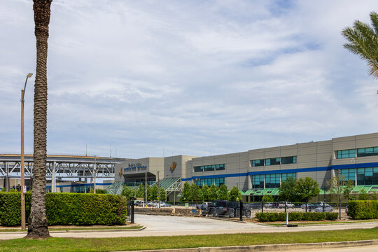 Ernest N. Morial Convention Center with lush green trees and grass, parked cars, blue sky and clouds in New Orleans Louisiana USA