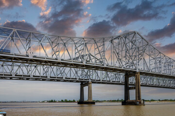 The Crescent City Connection bridge over the Mississippi River with lush green trees, plant and...