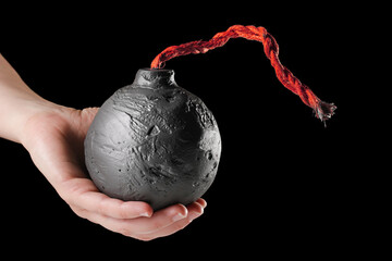 Hand holding round black bomb with red fuse ready to ignite. Bomb about to detonate symbolizing...