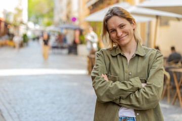 Portrait of happy young woman face smiling friendly glad expression looking at camera resting relaxation feel satisfied good news outdoors. Pretty blond adult girl tourist traveler on city street.