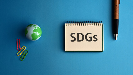 There is notebook with the word SDGs. It is an abbreviation for Sustainable Development Goals as eye-catching image.