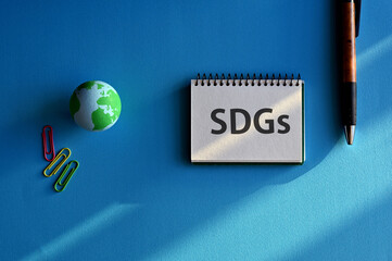 There is notebook with the word SDGs. It is an abbreviation for Sustainable Development Goals as eye-catching image.