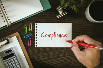 There is notebook with the word Compliance. It is as an eye-catching image.