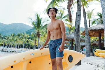 Naklejka premium Happy Asian Man Kayaking on a Tropical Beach Vacation