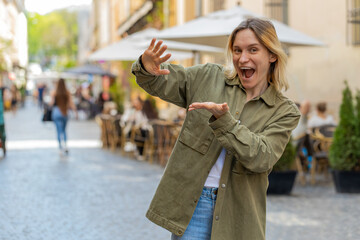 Cheerful rich tourist girl showing wasting throwing money around hand gesture, more tips earnings, big profit, win lottery, share, celebrate outdoor. Happy young woman standing on urban city street.
